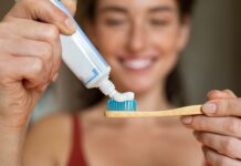 The Ingredient Your Teeth Already Know Woman applying toothpaste on bamboo toothbrush
