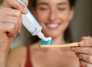 The Ingredient Your Teeth Already Know Woman applying toothpaste on bamboo toothbrush